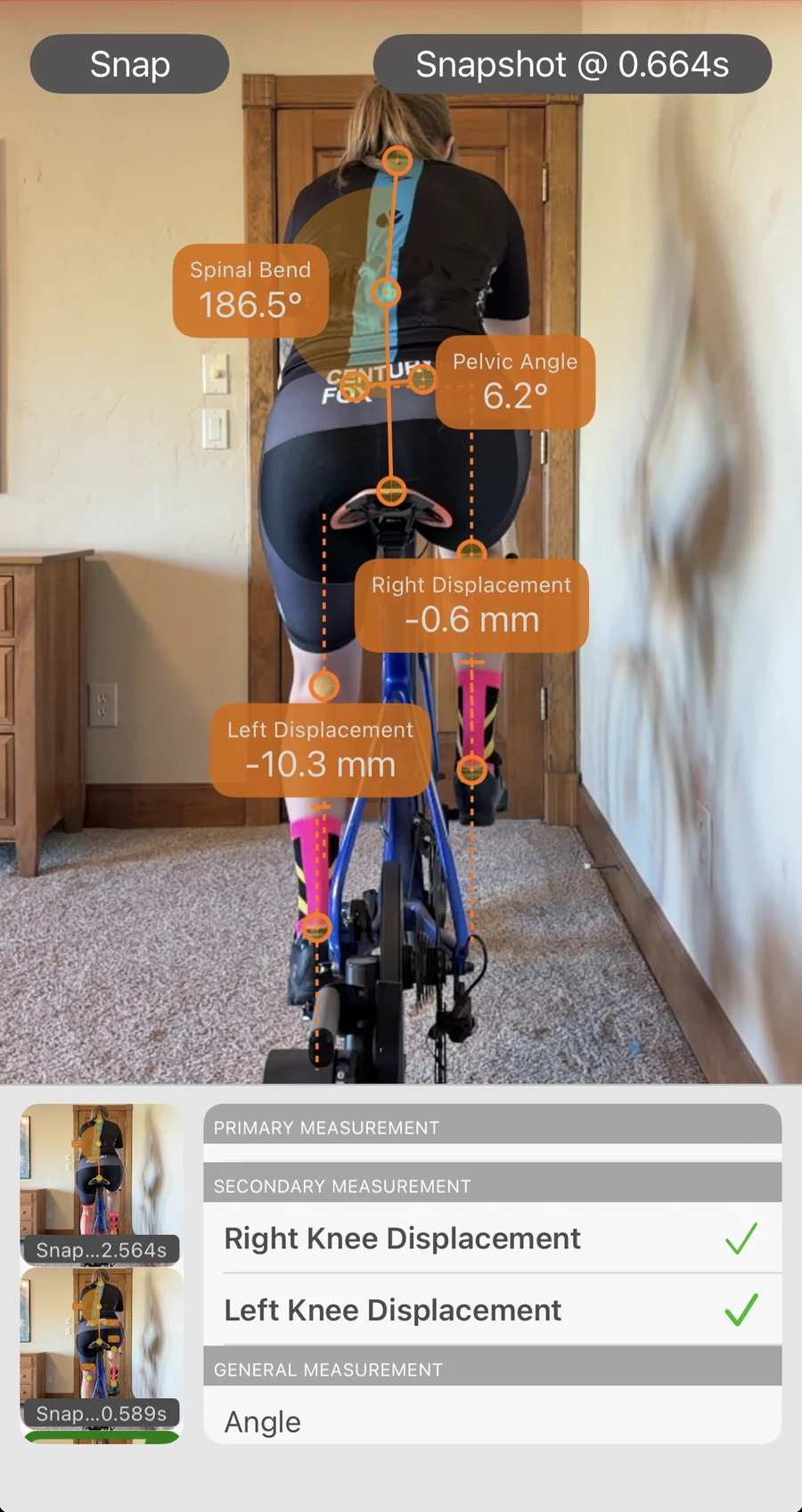 Bike Fast Fit Pro rear-view analysis: a tracked rider from behind, with left and right knee displacement in millimetres, pelvic angle, and spinal bend read off the frame, and the measurement list open below